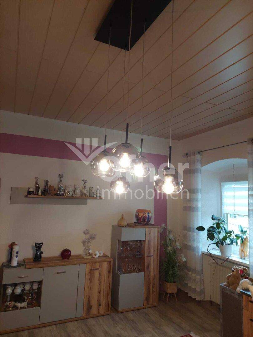 Essbereich mit moderner Hängelampe, Sideboards und Fenster.