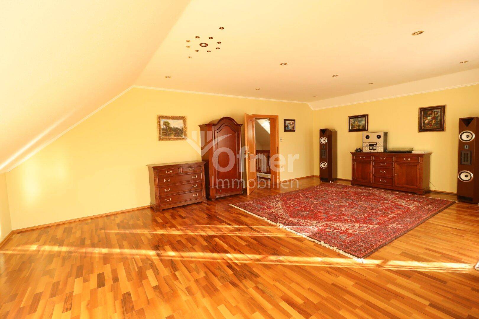 Geräumiges Wohnzimmer im Dachgeschoss mit Holzboden und traditionellen Möbeln.