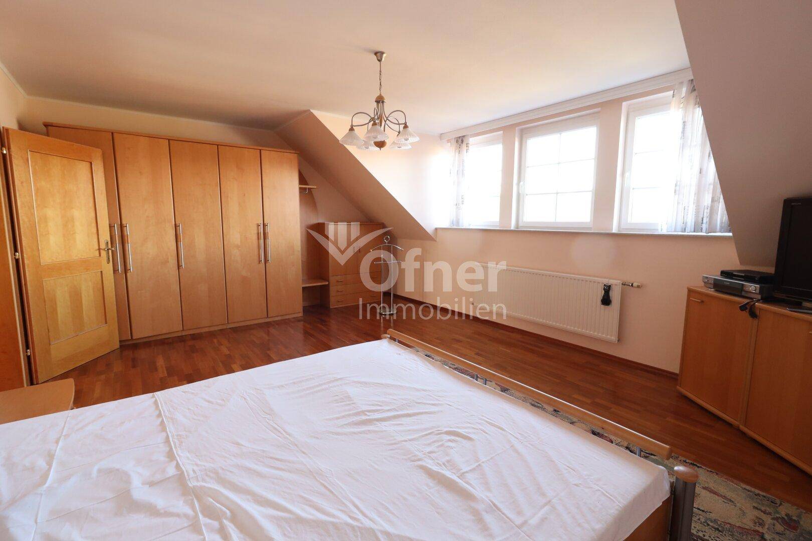 Schlafzimmer im Dachgeschoss mit Holzboden, Einbauschränken und Dachschrägen.