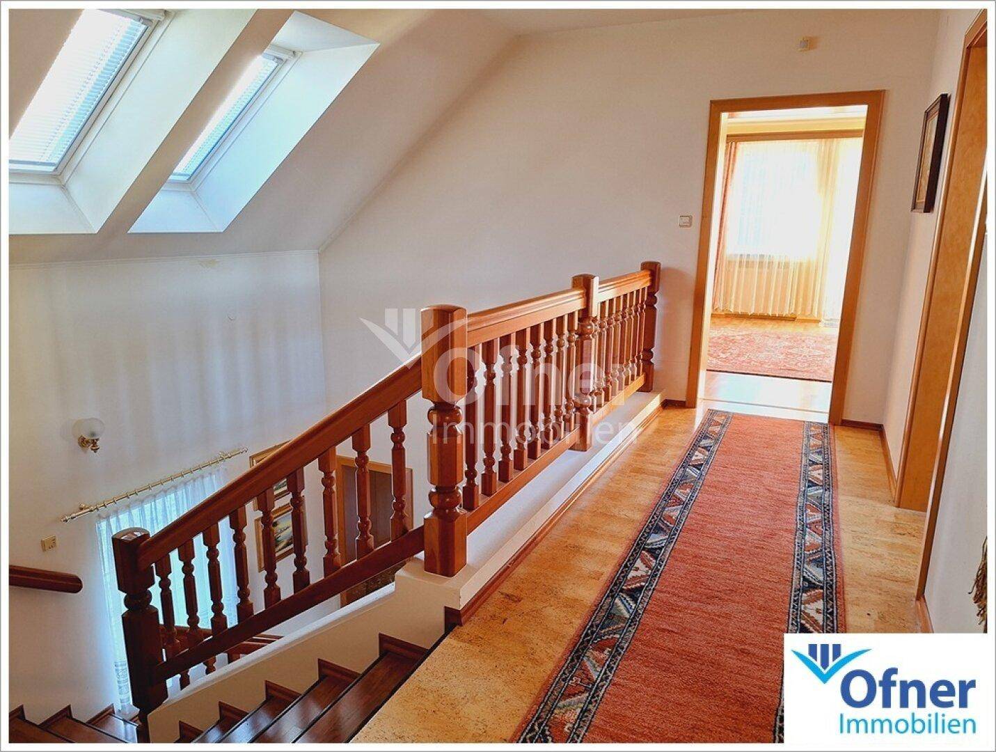 Flur im Dachgeschoss mit Holztreppe, Teppichläufer und Dachfenstern für natürliches Licht.