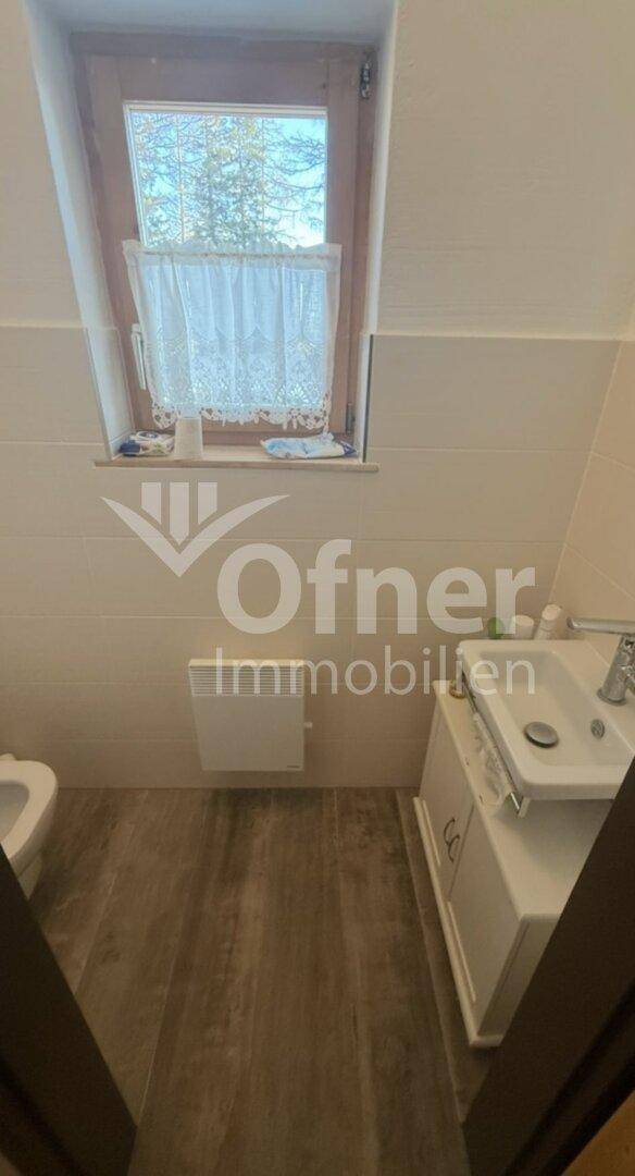 Helles Badezimmer mit Dachschräge, Waschbecken, Toilette und einem Fenster für Tageslicht.