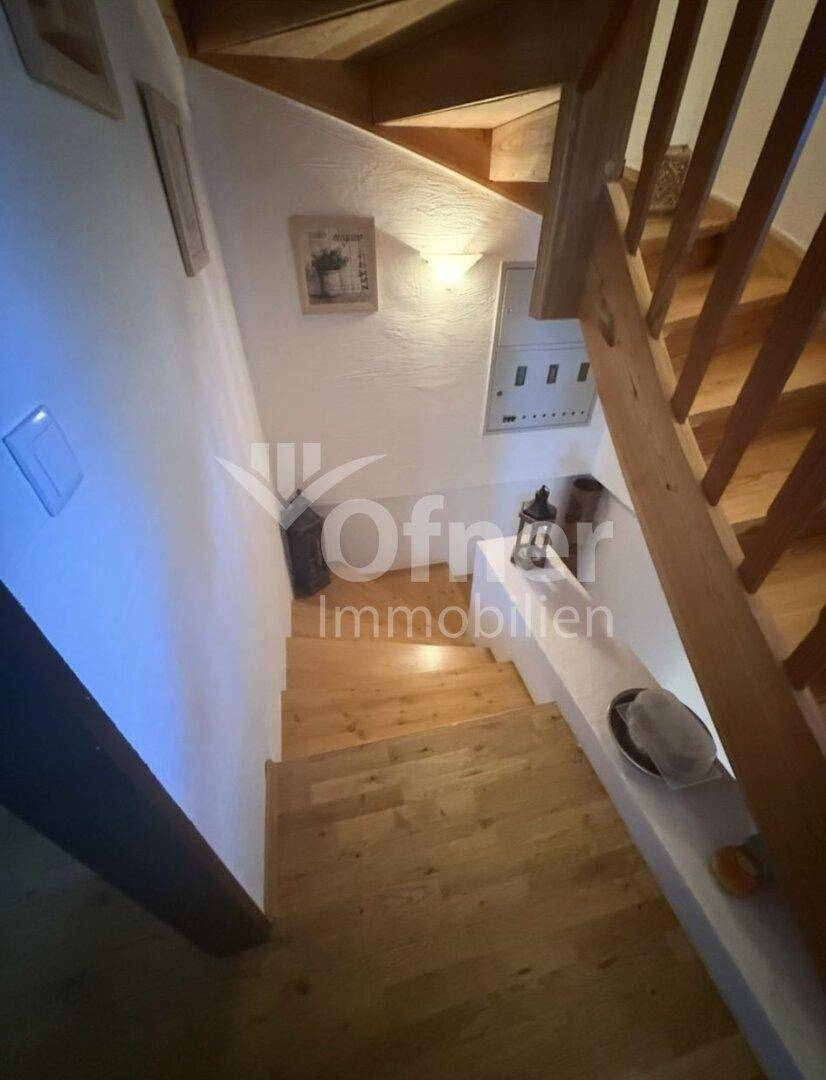 Helle Holztreppe mit weiß gestrichenen Wänden, die die verschiedenen Etagen des Hauses verbindet.