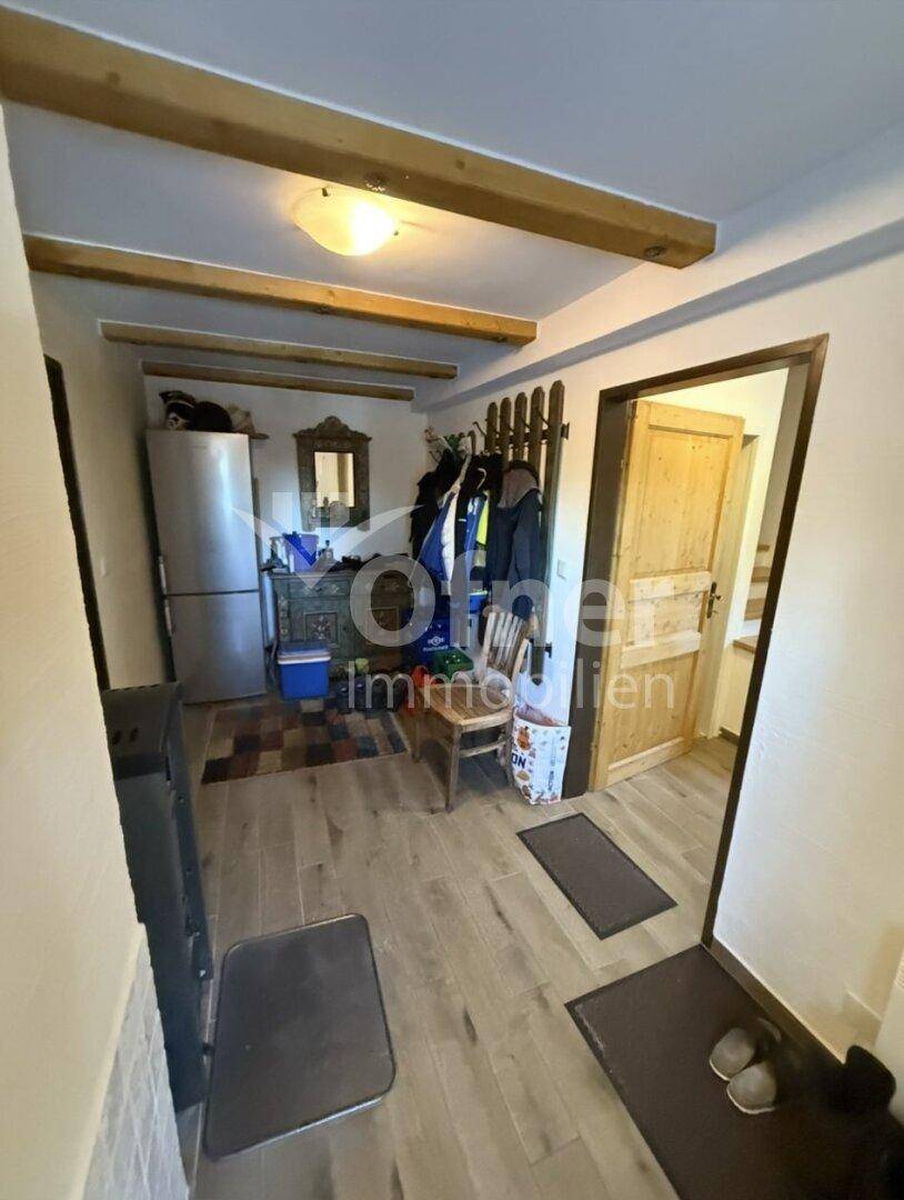 Geräumiger Flur mit Holzbalken, Garderobe und einem Kühlschrank, der zum Wohnbereich führt.