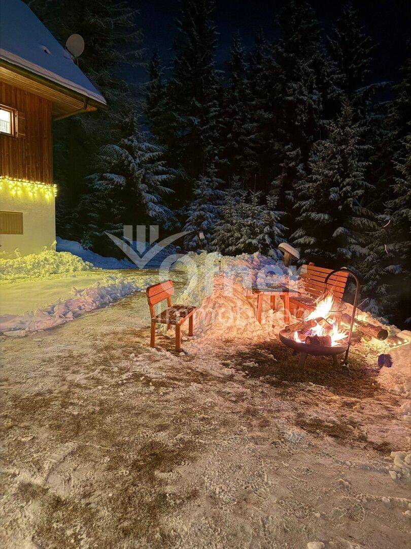 Gemütlicher Außenbereich mit Feuerstelle und Sitzgelegenheiten in der verschneiten Winternacht.