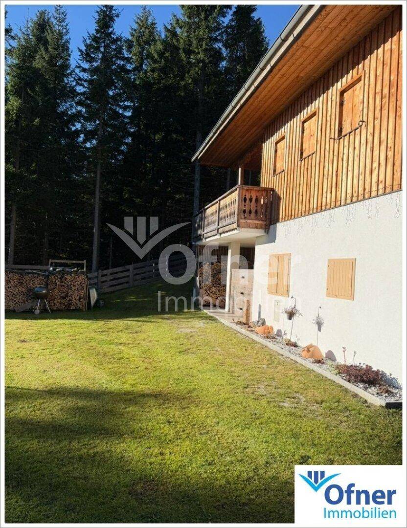 Charmantes Holzhaus mit gepflegtem Rasen und Holzstapel im Sommer.