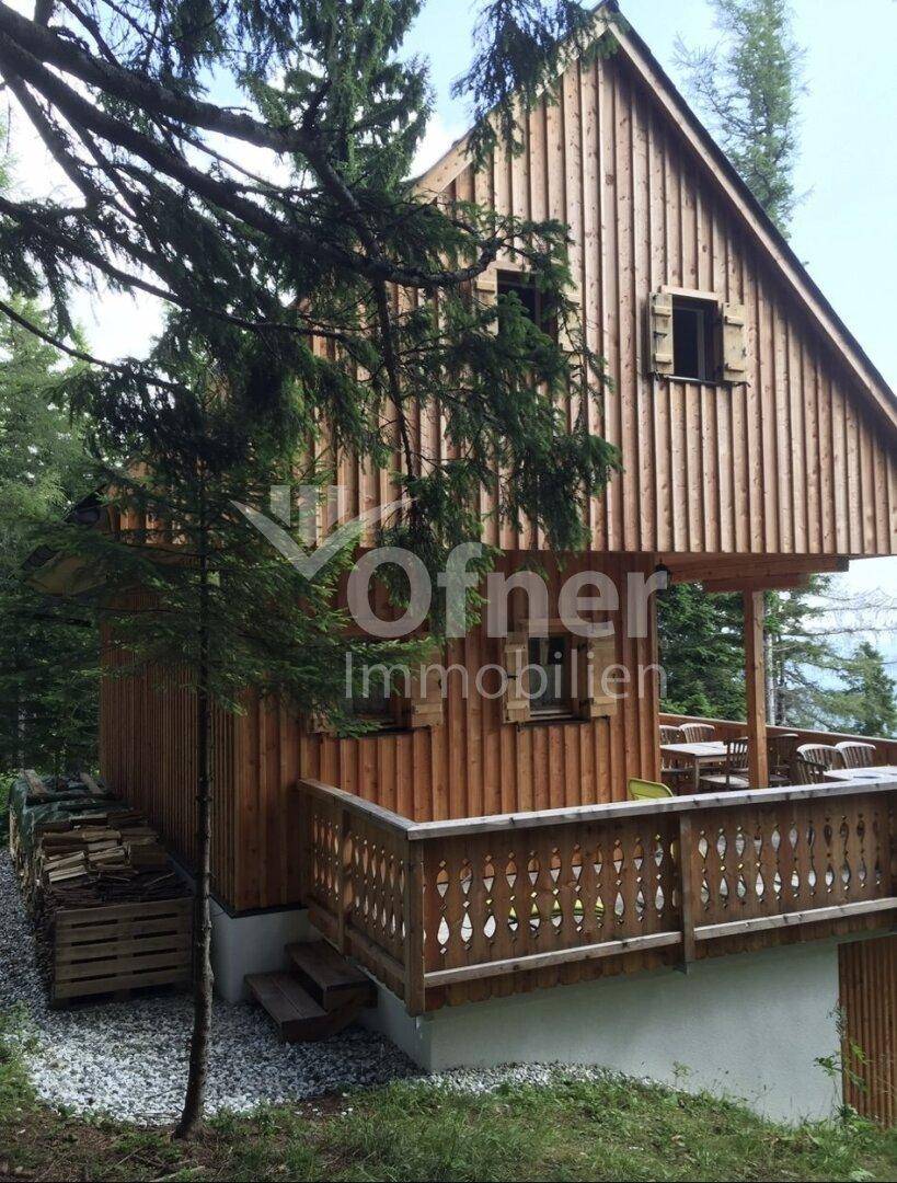 Traditionelles Holzhaus mit überdachtem Balkon und Holzstapel im Freien.
