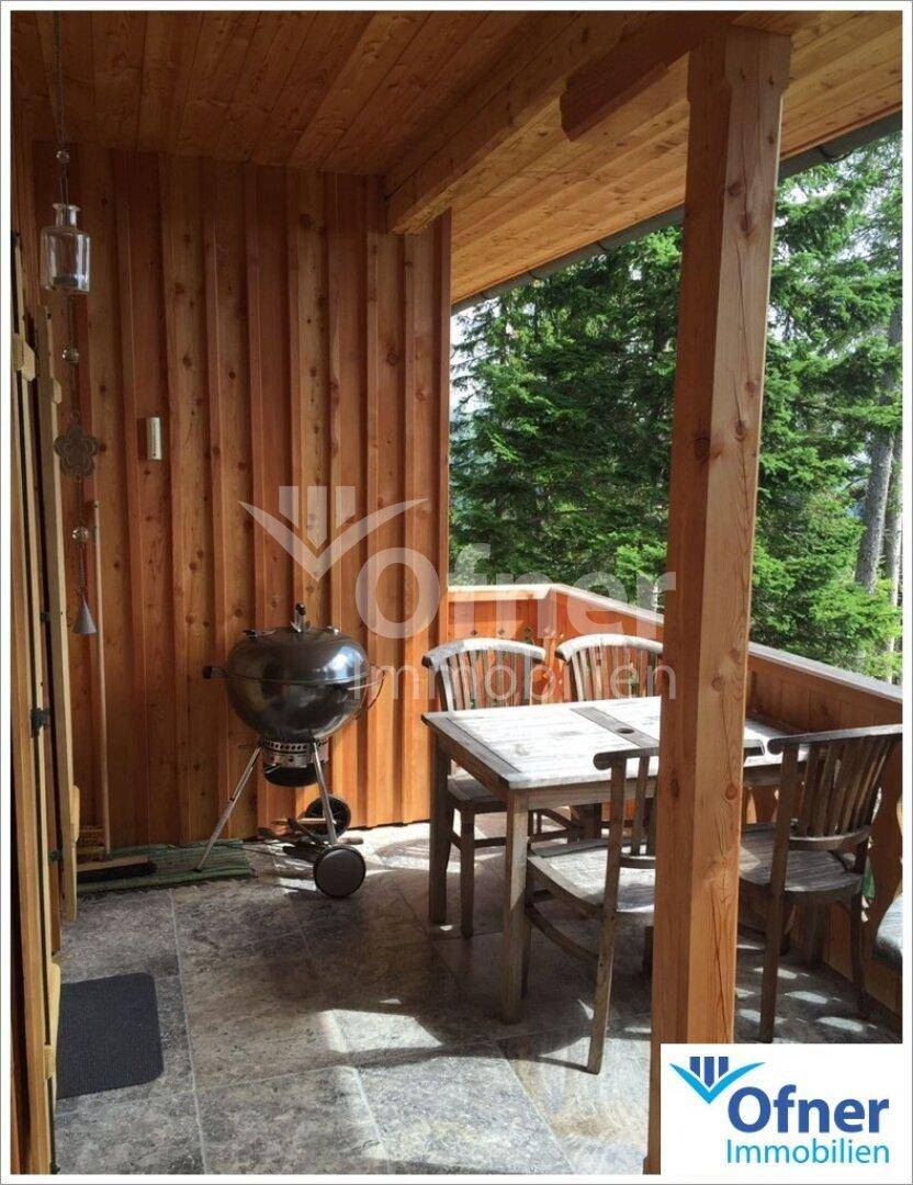 Überdachte Terrasse mit Holztisch, Stühlen und Grill, ideal für Mahlzeiten im Freien.