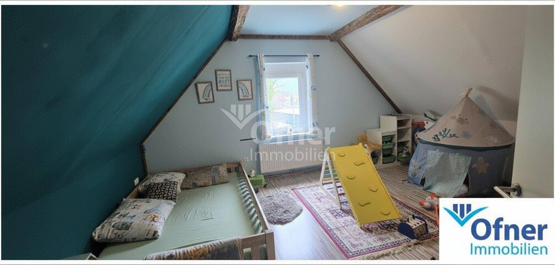 Farbenfrohes Kinderzimmer im Dachgeschoss mit schräger Wand, Spielbereich und Holzboden.