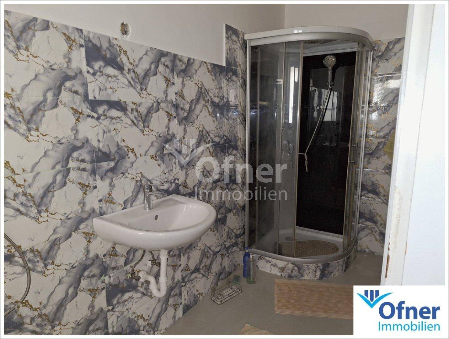 Badezimmer mit moderner Duschkabine und auffälligen Marmorfliesen an den Wänden.