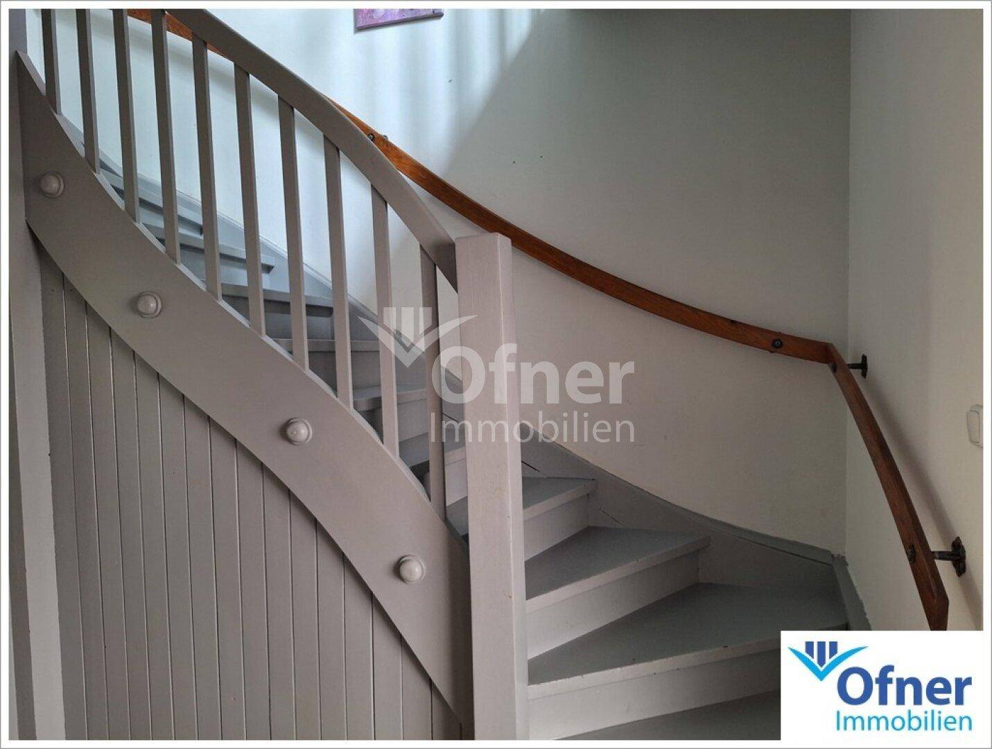 Holztreppe mit weißem Geländer und Handlauf, die in die obere Etage führt.