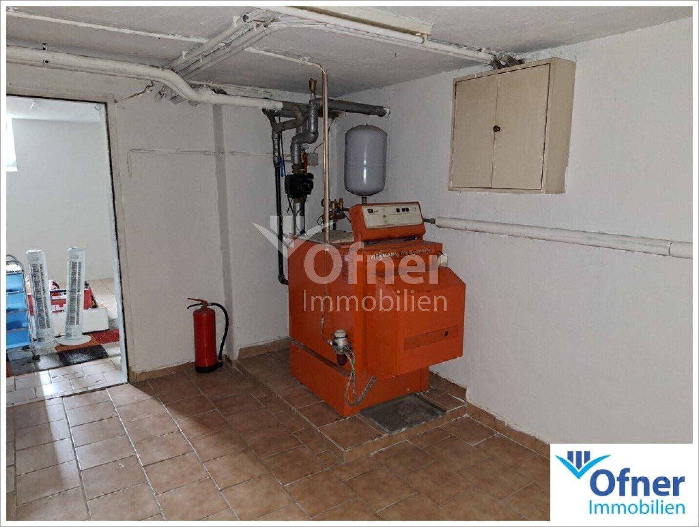 Heizungsraum im Keller mit einem großen Heizkessel und Fliesenboden.