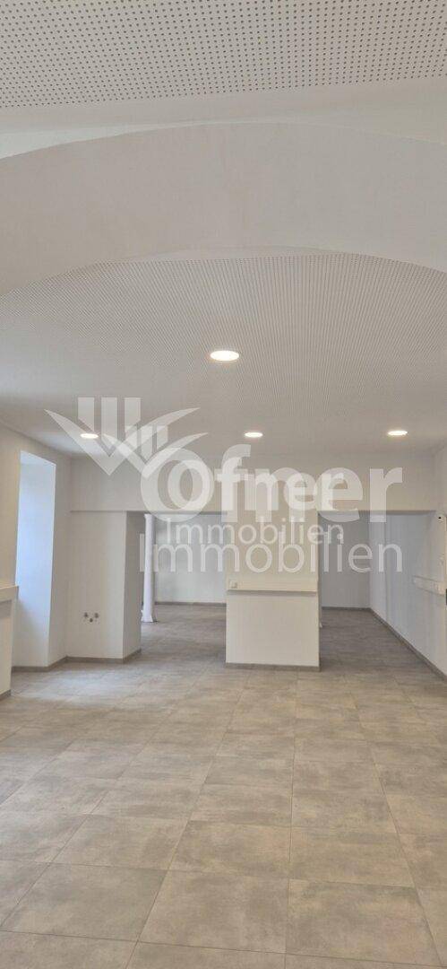 Geräumiger, heller Geschäftsraum mit Fliesenboden, gewölbter Decke und modernen Einbaustrahlern.