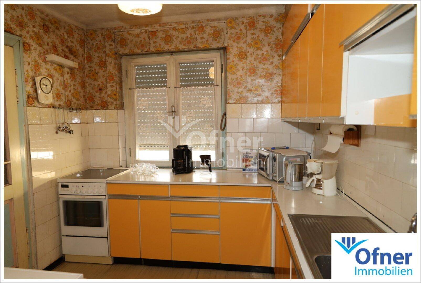 Kleine Küche im Vintage-Stil mit orangefarbenen Schränken, floraler Tapete und Fliesen.
