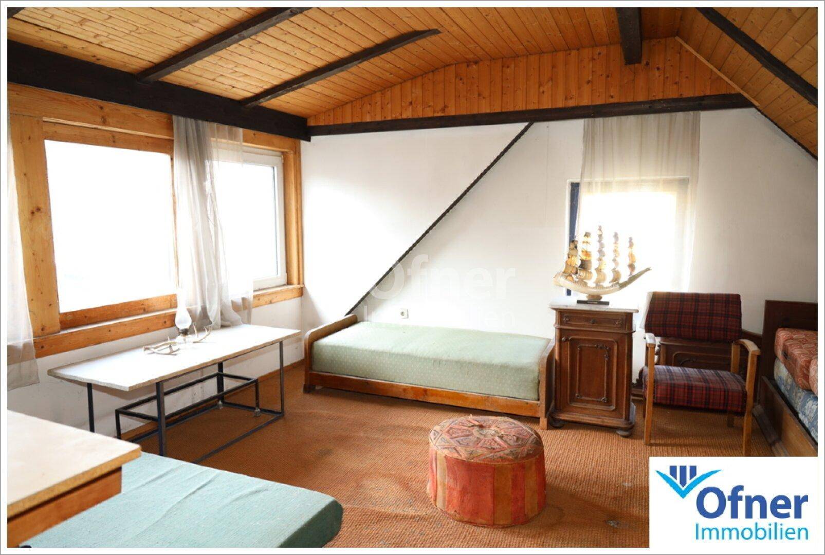 Helles Schlafzimmer im Dachgeschoss mit schrägen Wänden, Holzdecke und zwei Einzelbetten.
