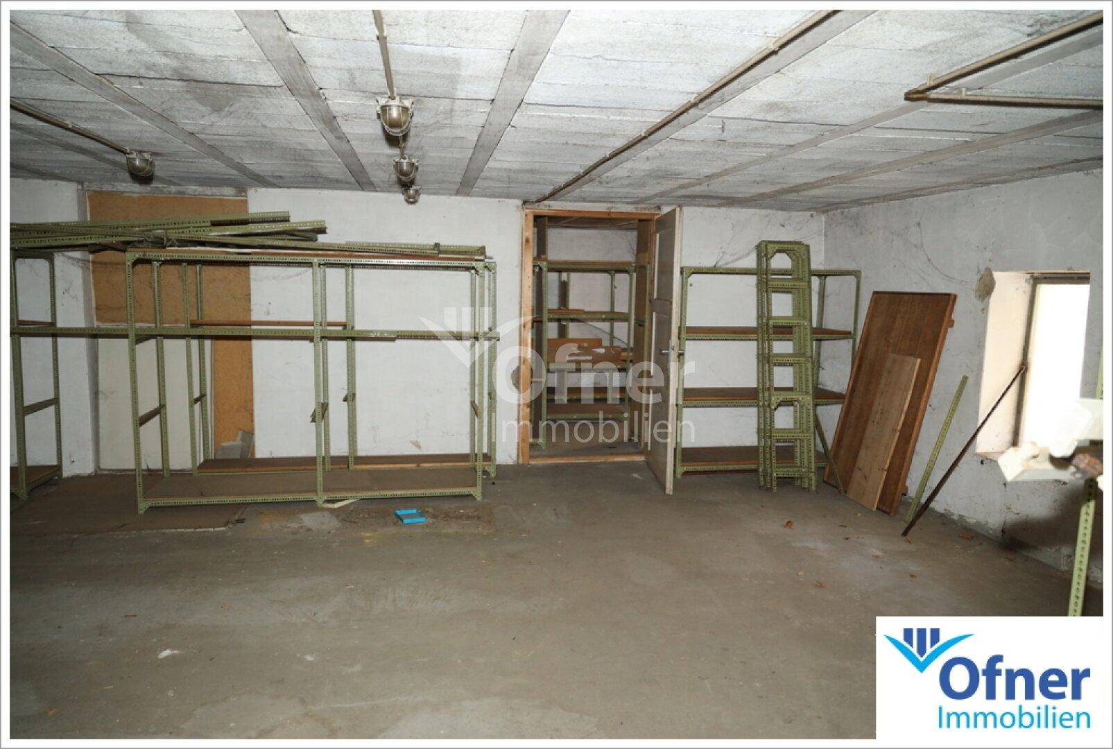 Großer Lagerraum mit Regalen und Betonboden, möglicherweise im Keller oder Erdgeschoss.
