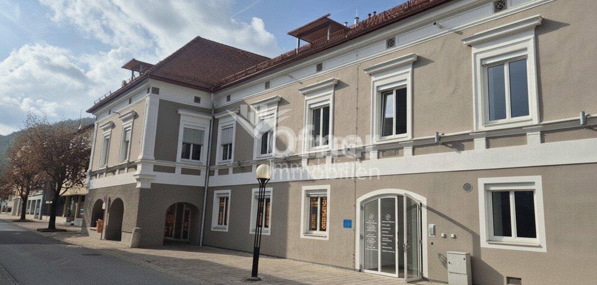 Ansicht der Gebäudefassade mit Eingangsbereich und Fenstern, die auf die Straße blicken.