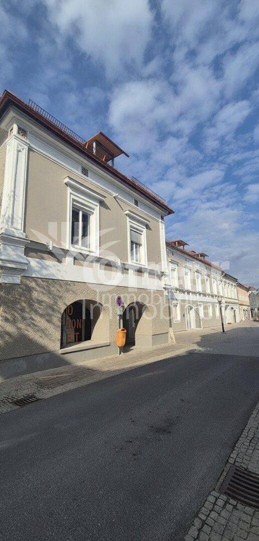 Historische Gebäudefassade mit gewölbten Eingängen und Fenstern, die auf die Straße blicken.