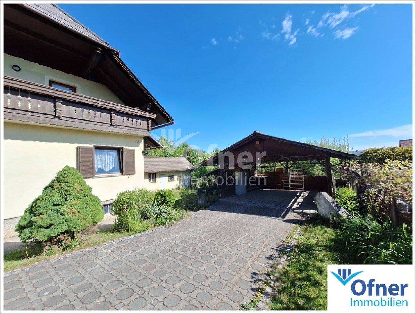 Einfahrt mit gepflastertem Weg und überdachtem Carport neben dem Haus.