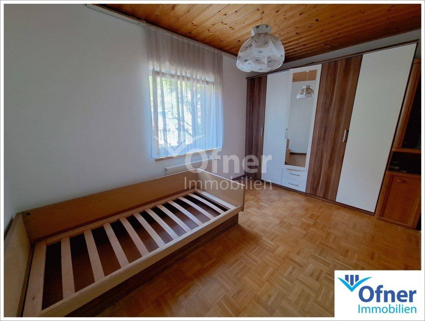 Helles Schlafzimmer mit Parkettboden, Holzdecke und Kleiderschrank mit Spiegeltür.