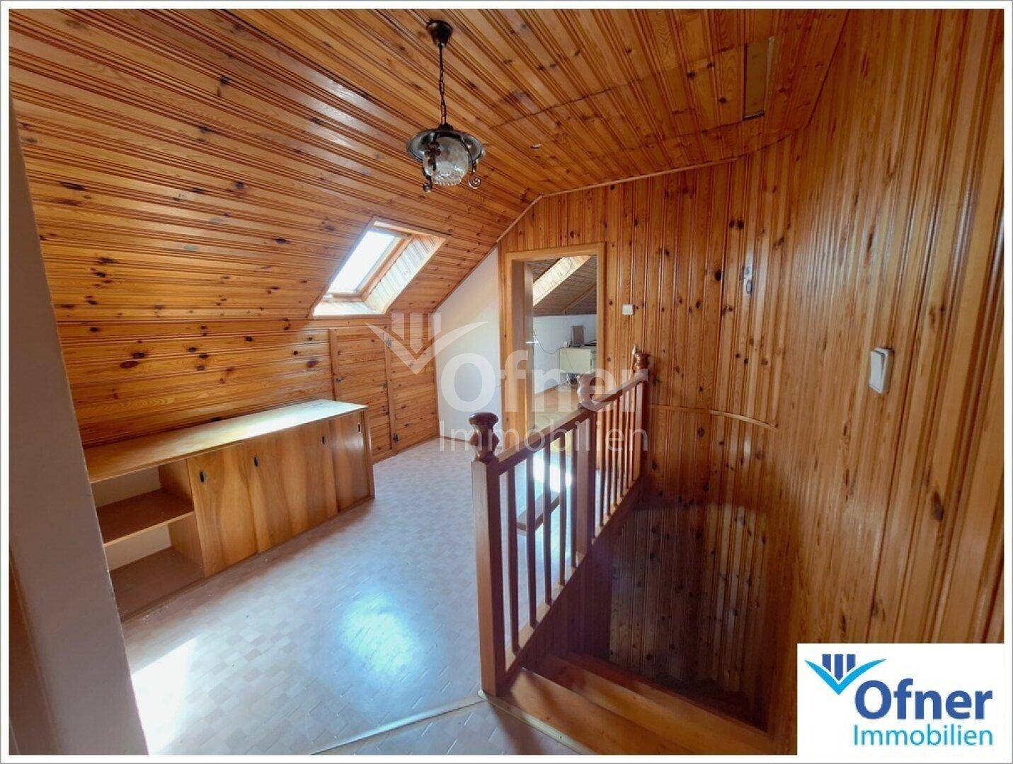 Heller Flur im Obergeschoss mit Holzvertäfelung, Dachschrägen und Dachfenstern.