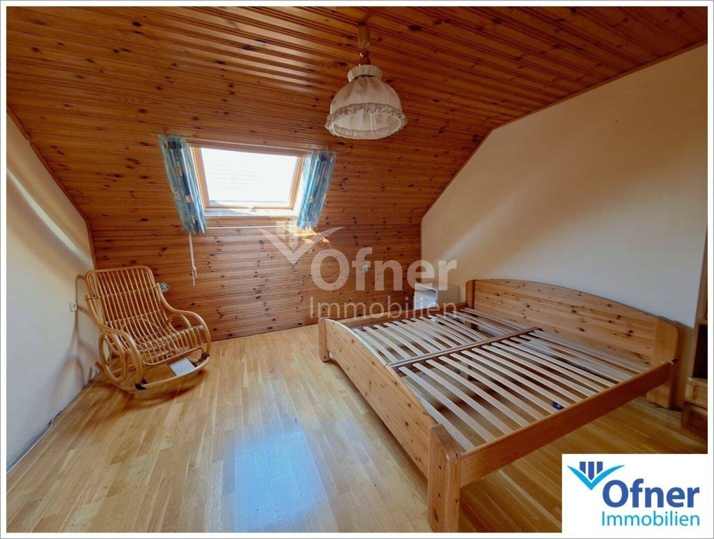 Gemütliches Schlafzimmer mit Holzbett, Parkettboden und Dachfenster.