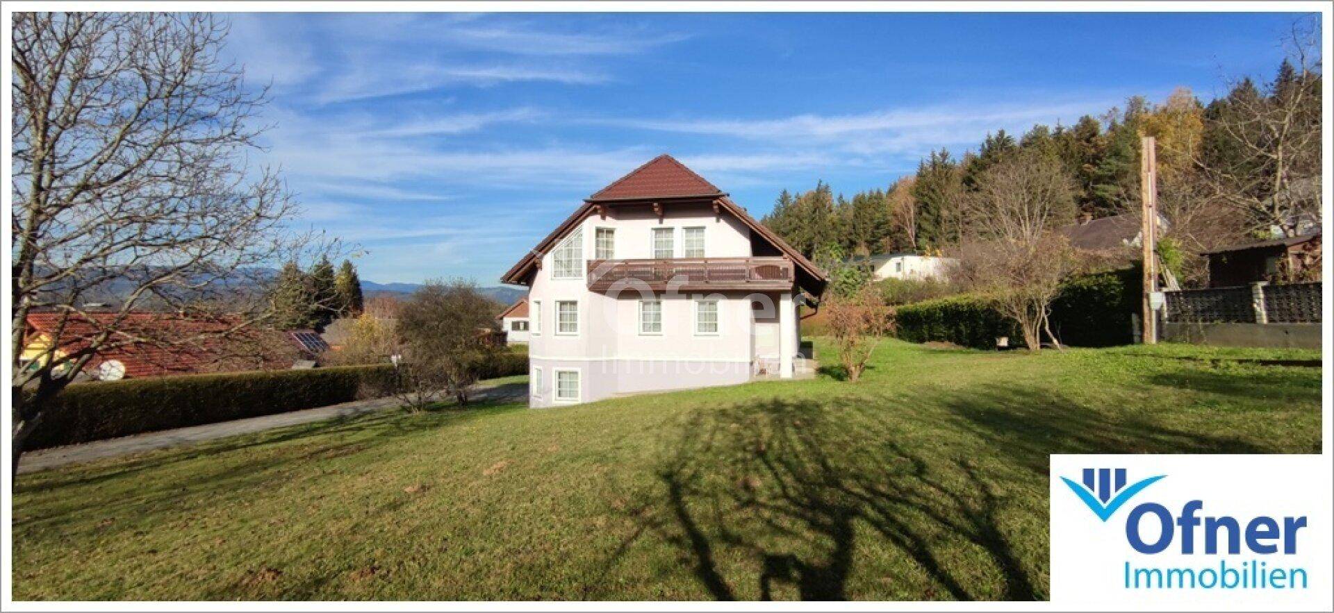 Einfamilienhaus mit Satteldach auf einem weitläufigen Grundstück mit grüner Wiese und Bäumen.