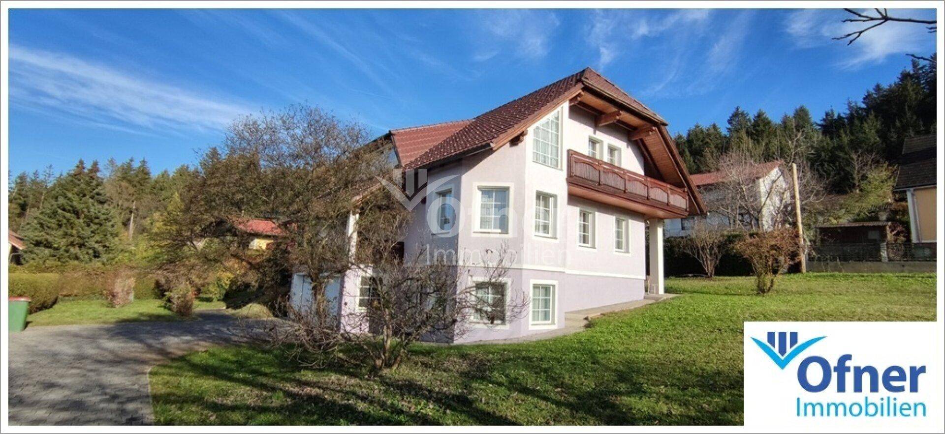 Ansicht des Einfamilienhauses mit Balkon und gepflegter Fassade, umgeben von Bäumen und Grünflächen.