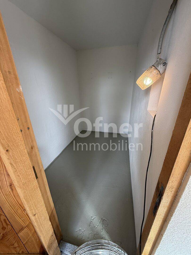 Kleiner, einfacher Abstellraum im Dachgeschoss mit schrägen Wänden und sichtbaren Holzbalken.