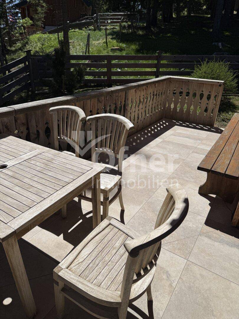 Detailansicht der Holzloggia mit Gartenmöbeln und dem traditionellen Holzgeländer.