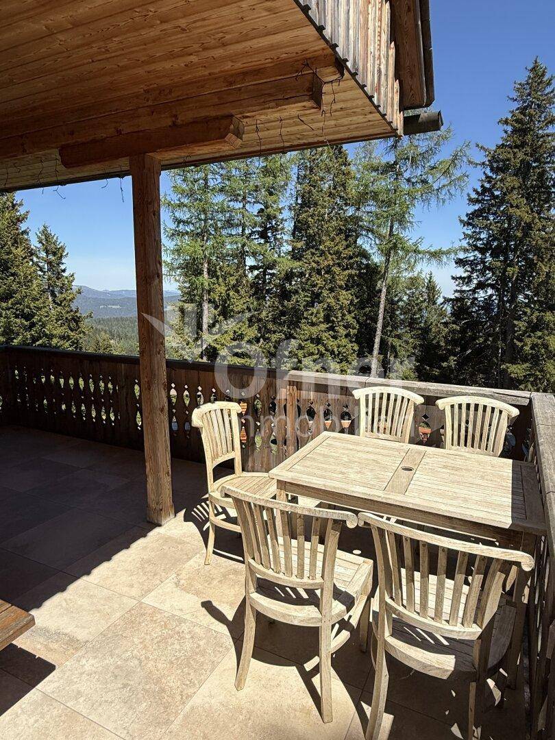 Geräumige Holzloggia mit Esstisch und Stühlen, ideal für Mahlzeiten im Freien mit Bergblick.