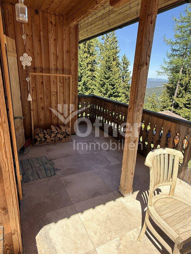Sonnige Holzloggia mit rustikalem Geländer, Fliesenboden und Panoramablick auf die Natur.