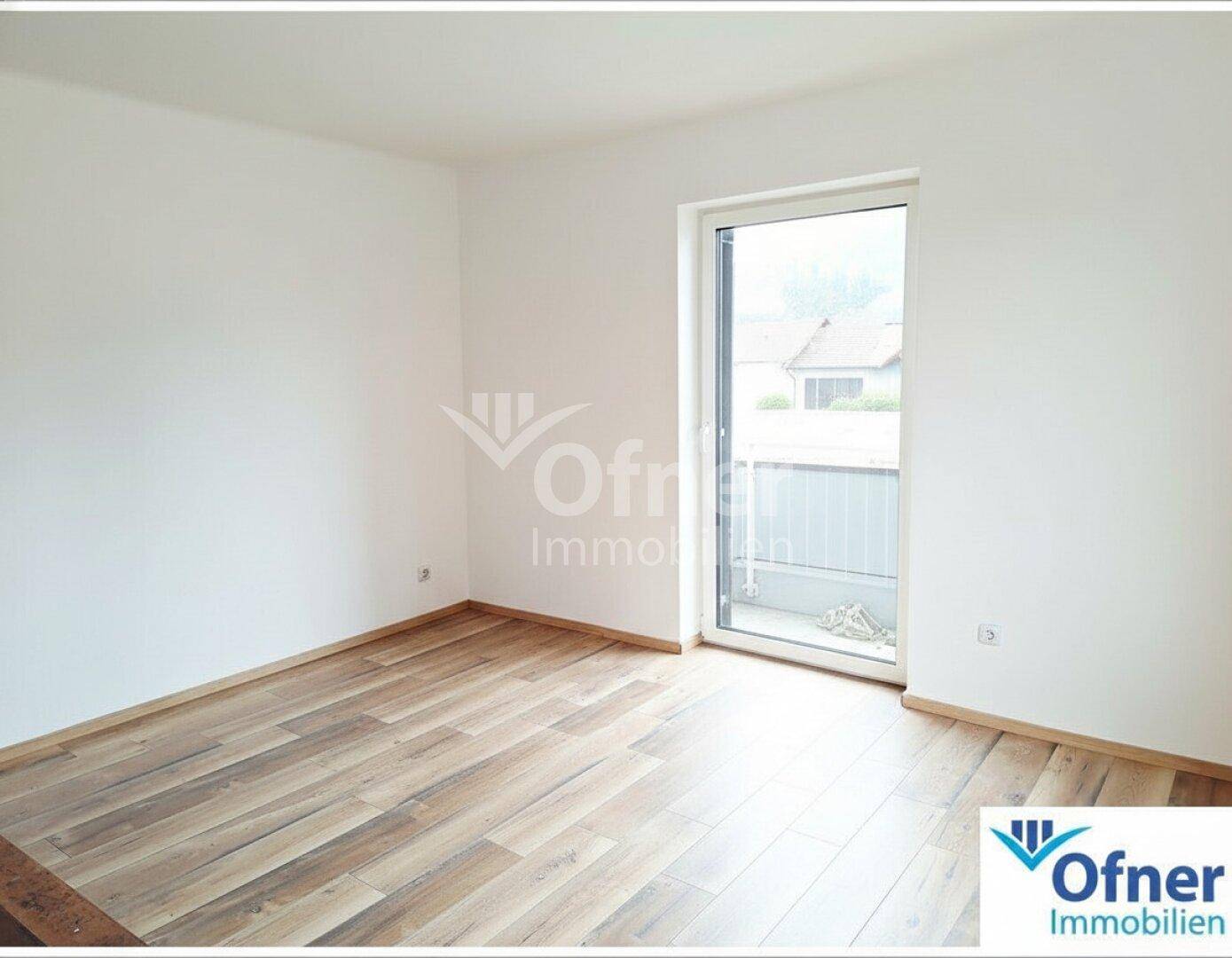 Helles Zimmer mit Holzboden und Zugang zu einem kleinen Balkon, ideal für ein Schlafzimmer.