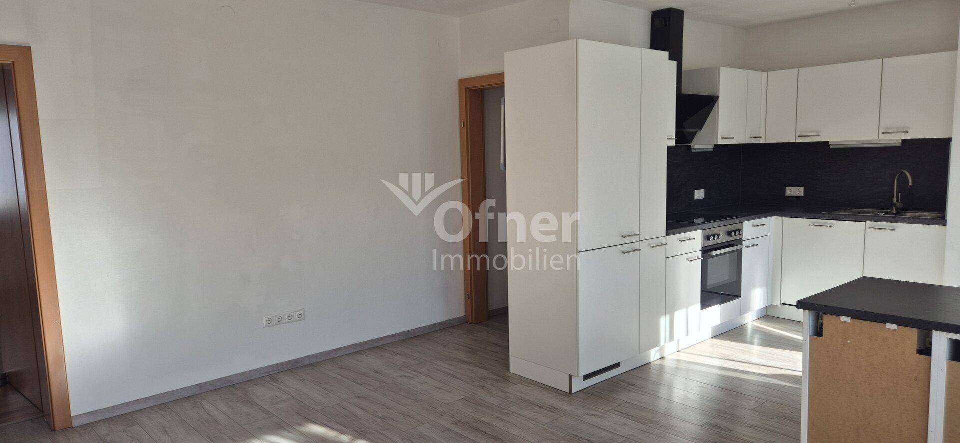 Moderne Einbauküche mit weißen Schränken, dunkler Arbeitsplatte und integrierten Geräten.