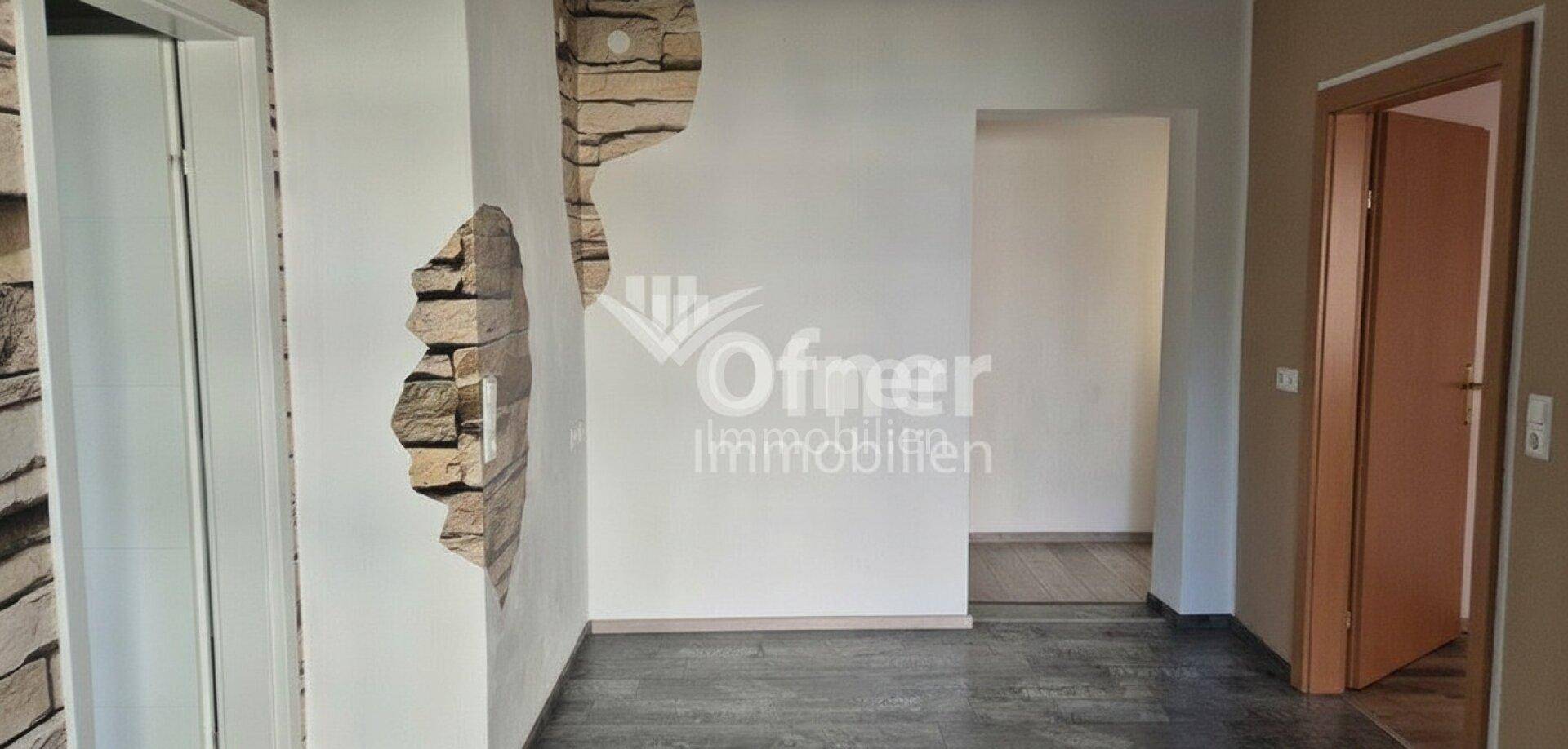 Flur oder Übergangsbereich mit dekorativer Steinwand und mehreren Türen.