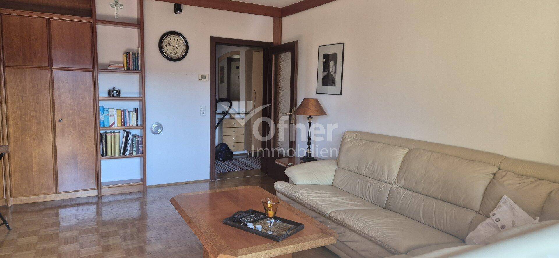 Heller Wohnbereich mit bequemer Couch, Bücherregal und Zugang zum Treppenhaus.