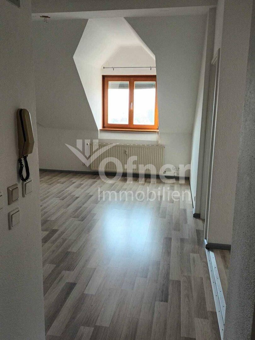Heller Flur mit Laminatboden und Gegensprechanlage, der zu einem weiteren Raum führt.