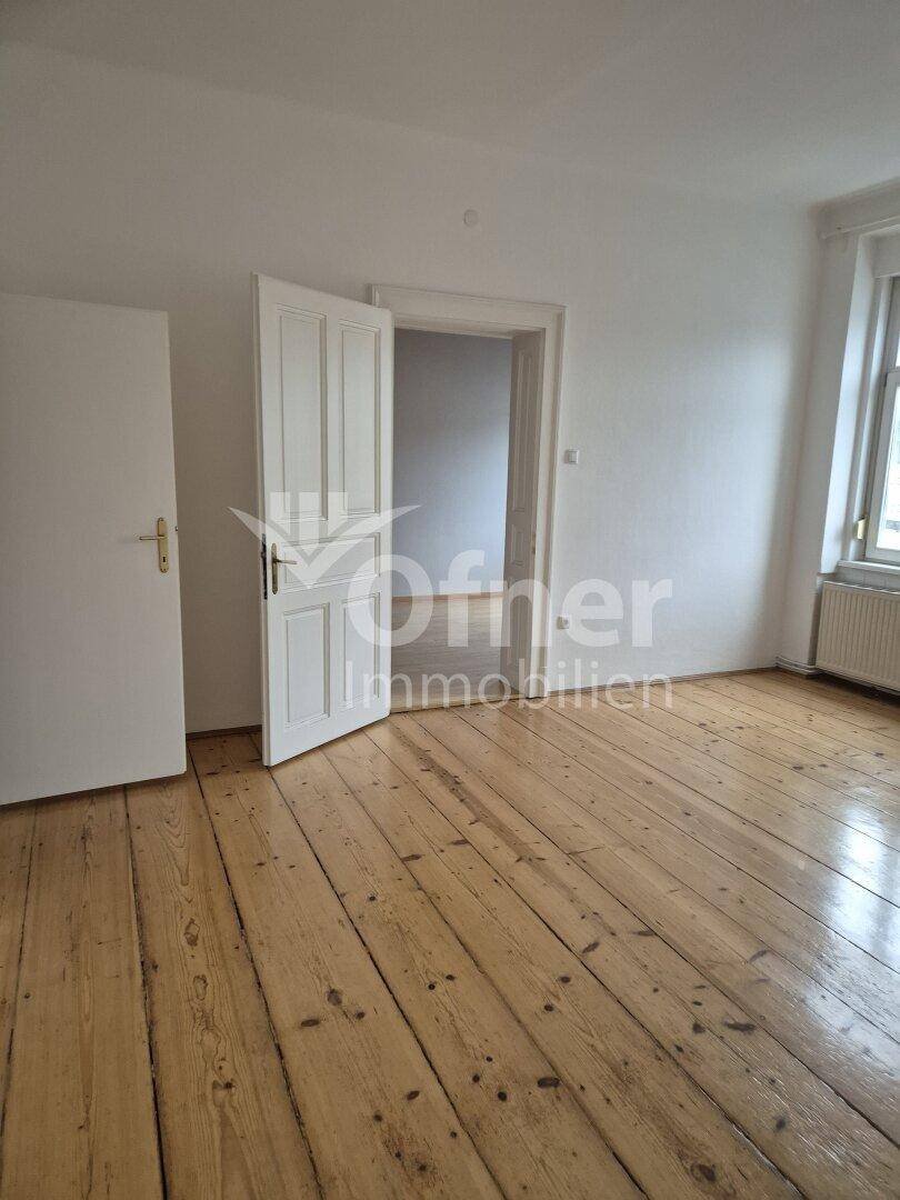 Geräumiges Zimmer mit breiten Holzplankenböden und weiß gestrichenen Wänden.