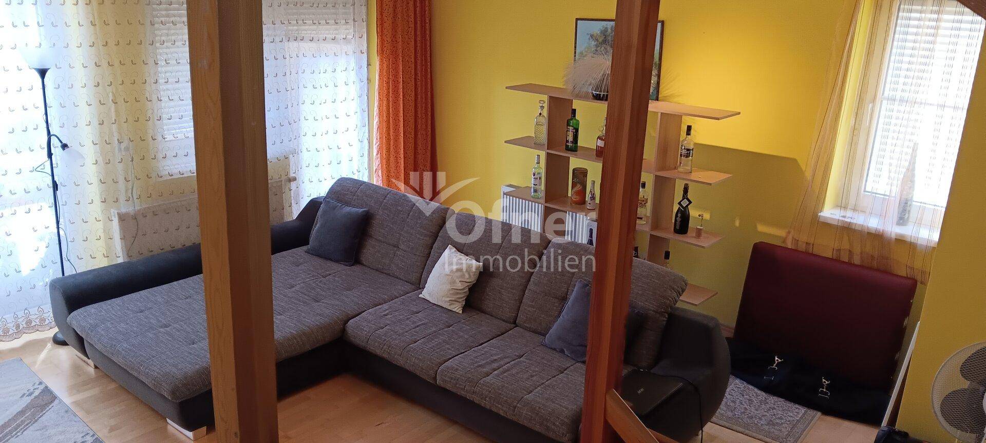 Helles Wohnzimmer mit großem Ecksofa, Holzbalken und gelben Wänden.