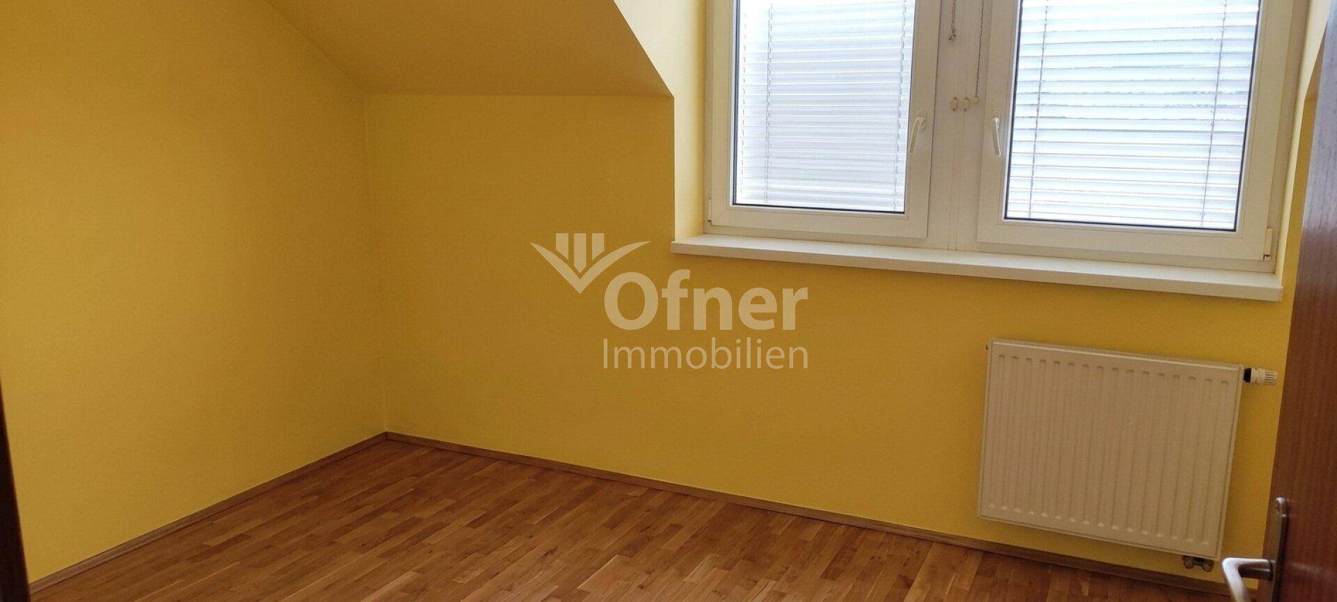 Helles Zimmer mit gelben Wänden, Holzfußboden und großem Fenster.