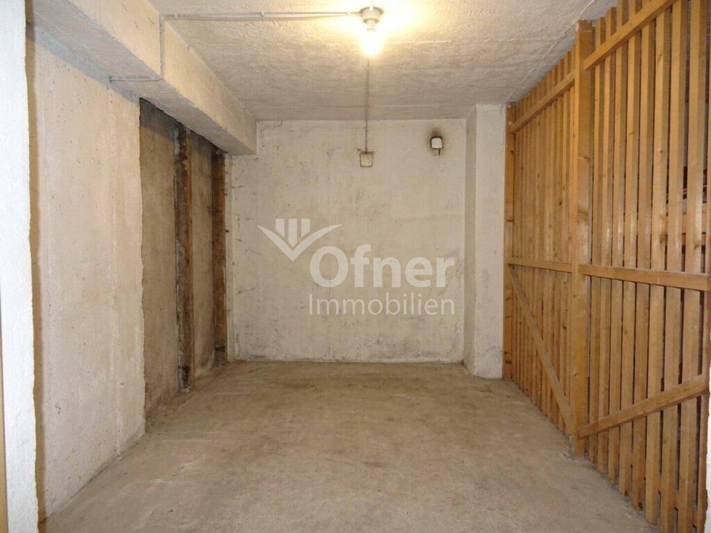 Geräumiger Kellerraum mit Betonboden und Holzabtrennungen für Lagerzwecke.
