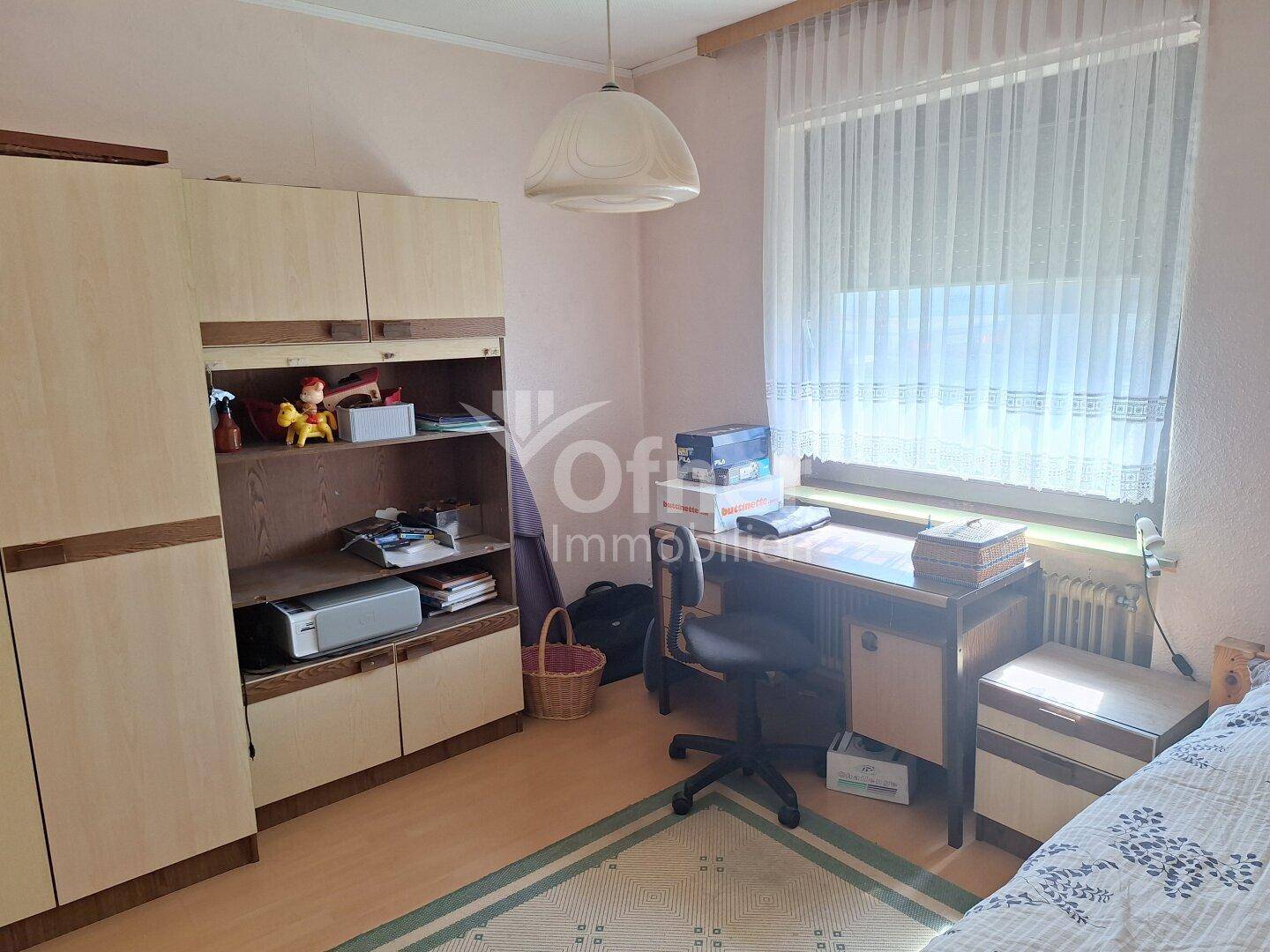 Schlafzimmer mit Schreibtisch, Einbauschränken und großem Fenster.