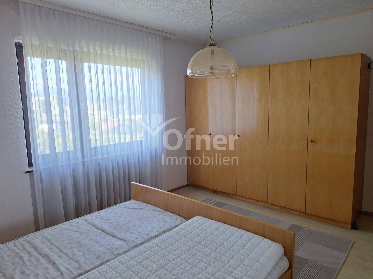 Schlafzimmer mit zwei Einzelbetten, großem Kleiderschrank und hellem Fenster.