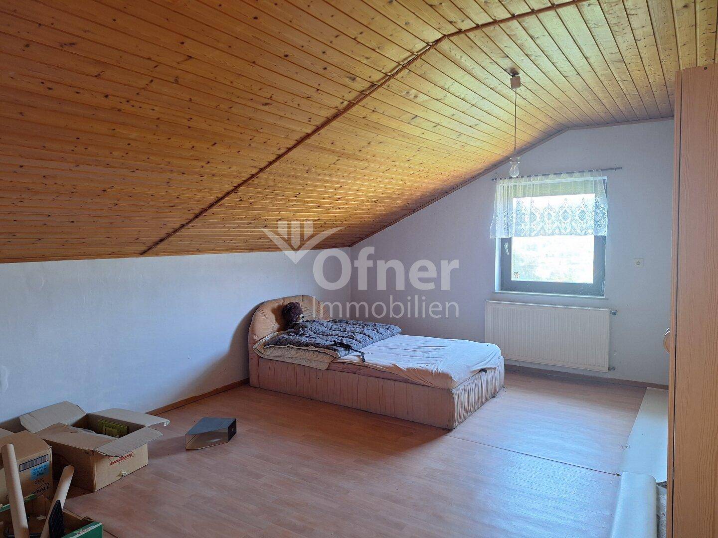Gemütliches Schlafzimmer im Dachgeschoss mit Holzdecke und Dachschräge.