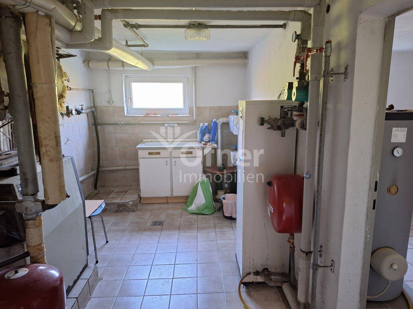 Hauswirtschaftsraum im Keller mit Heizungsanlage, Waschbecken und Fliesenboden.