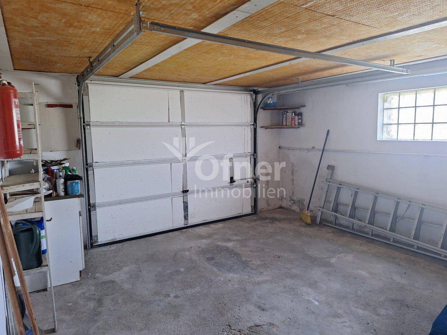 Geräumige Garage mit Rolltor und Betonboden, ideal für ein Fahrzeug.