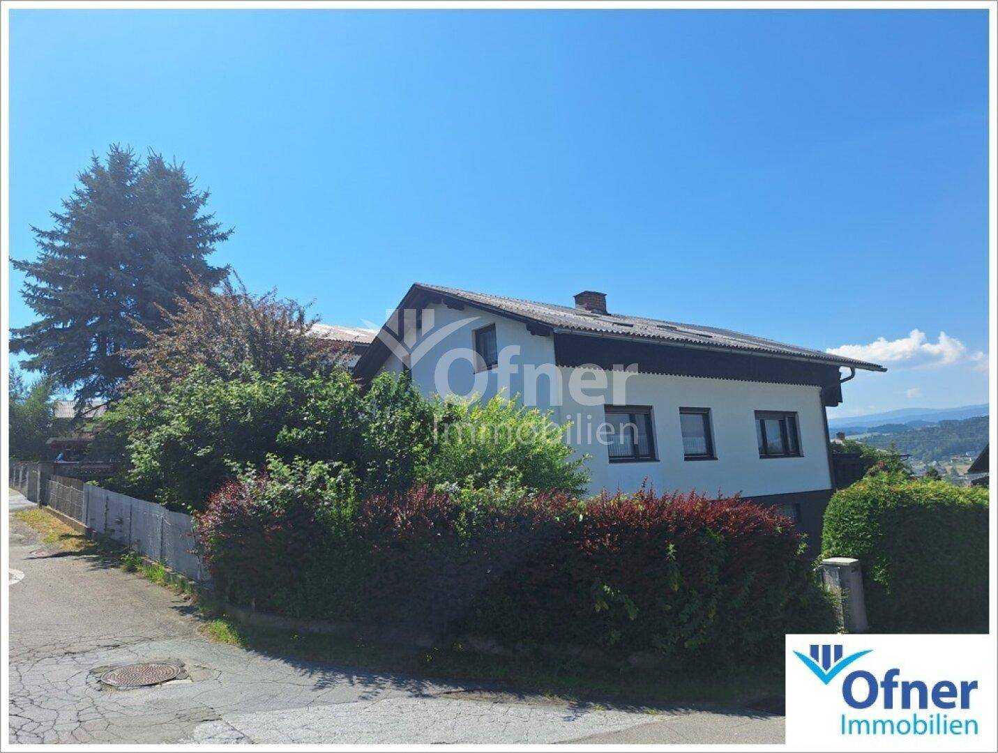 Seitenansicht des Hauses mit üppiger Bepflanzung und Blick auf die Umgebung.