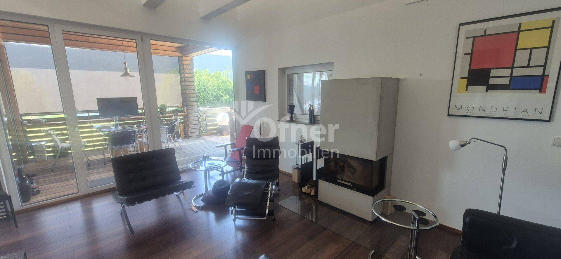 Heller Wohnbereich mit Kamin und großzügigem Zugang zur Außenterrasse.