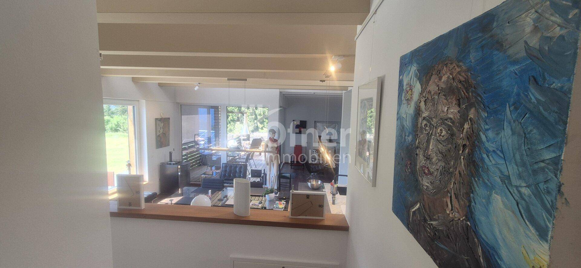 Blick von oben in den offenen Wohn- und Essbereich mit großen Fenstern.