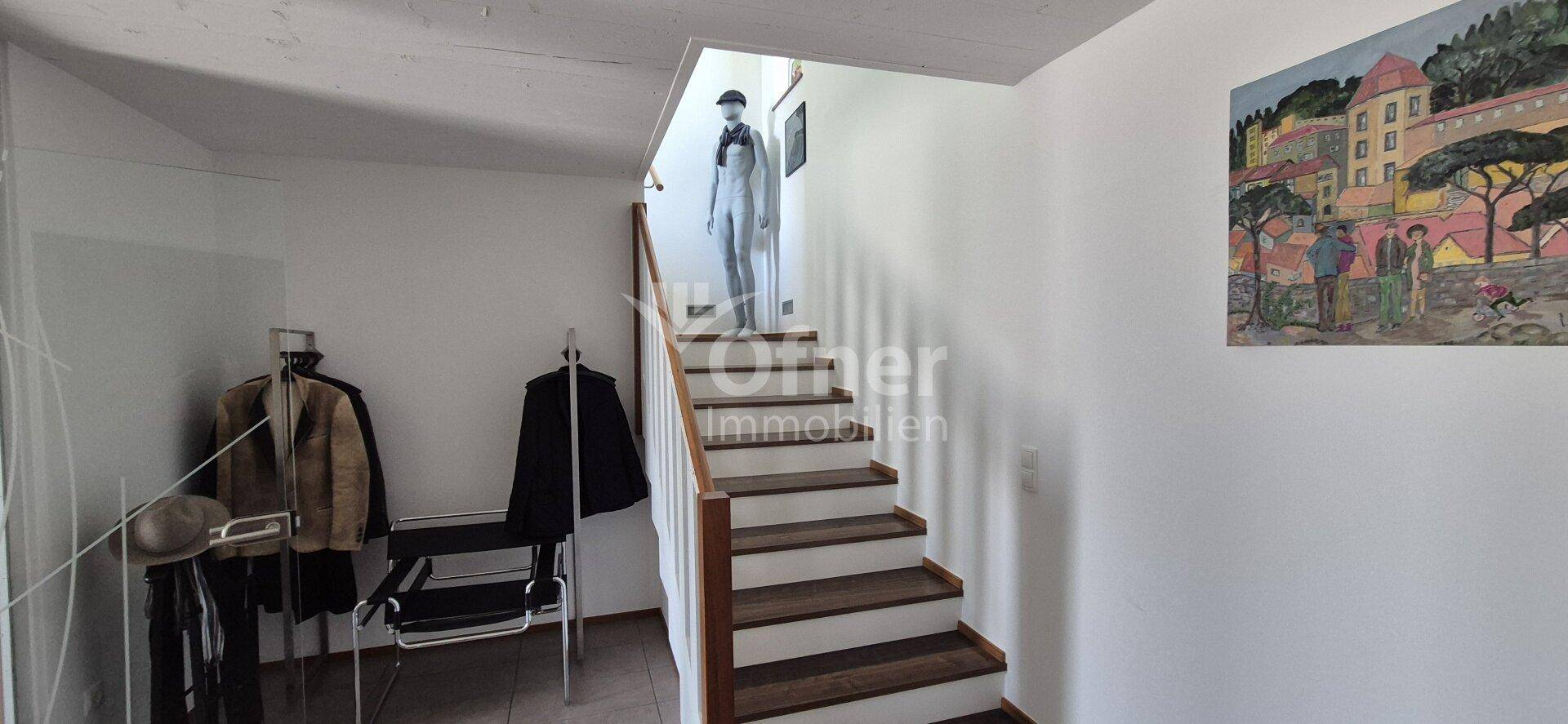 Heller Treppenaufgang mit Holzstufen und weiß gestrichenen Wänden.