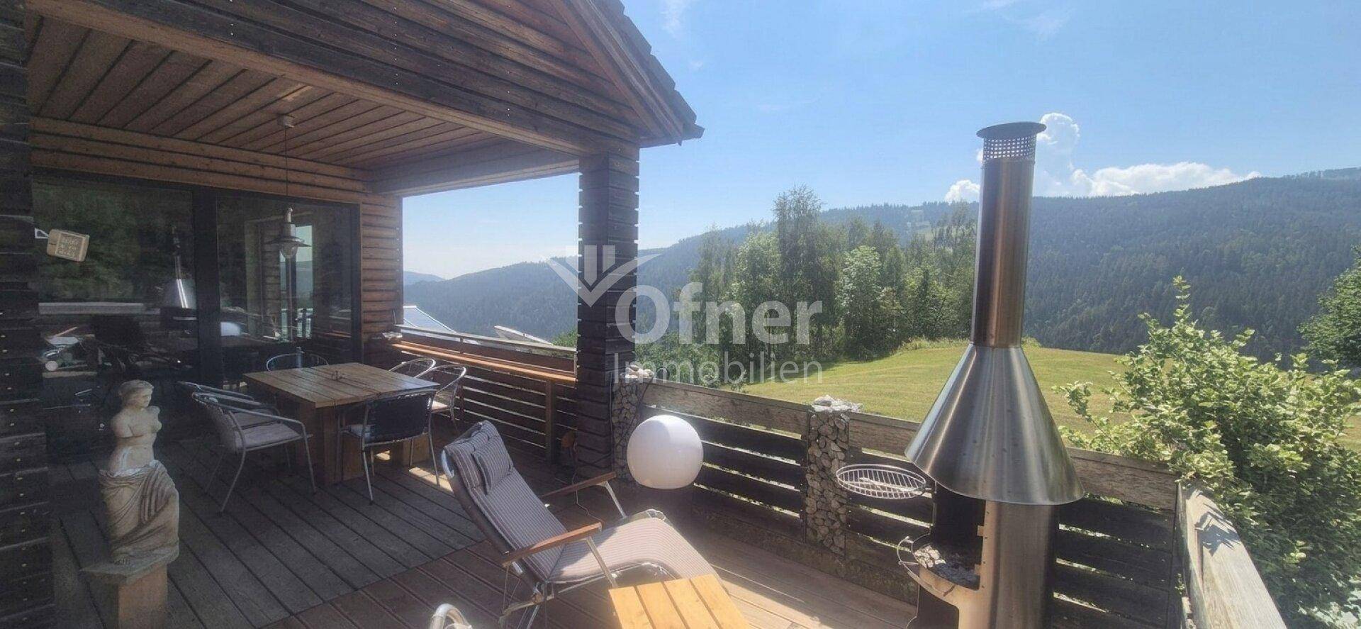 Große überdachte Holzterrasse mit Esstisch, Grill und Panoramablick.
